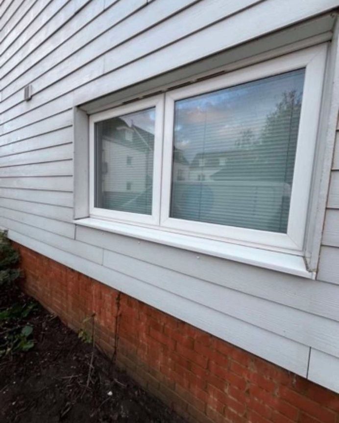 Pale grey weatherboard cladding and white uPVC window, clean after a wash