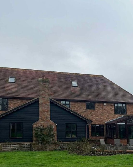 Large brick house with a dark, moss-stained clay tile roof before cleaning
