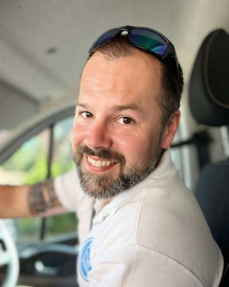 Tom, owner of TMF Exterior Cleaning, smiling in the cab of his work van